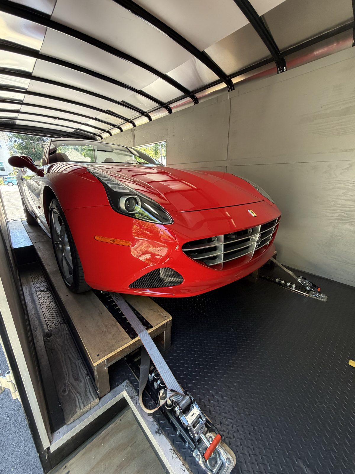Red Ferrari California strapped down inside the enclosed trailer