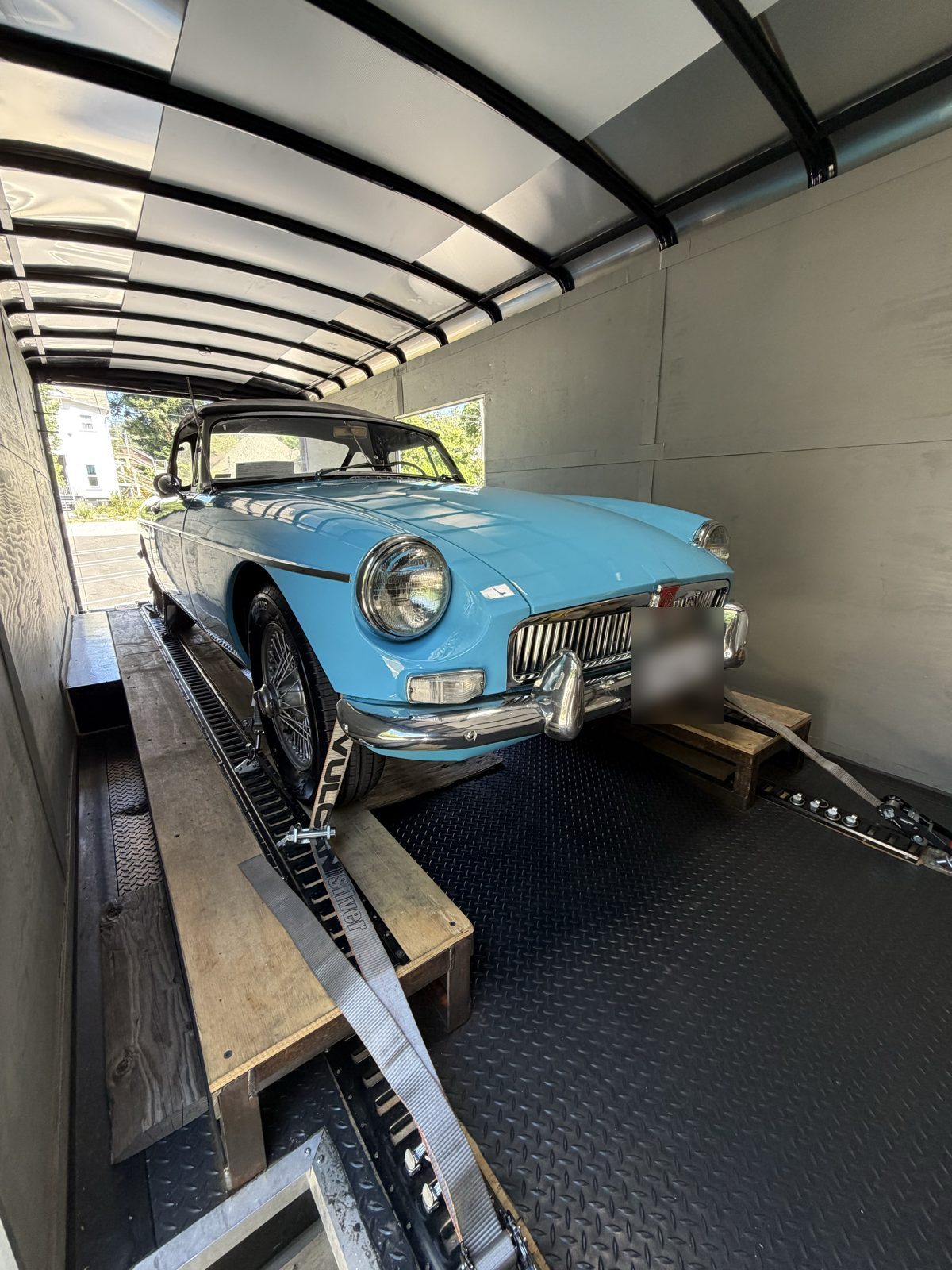 Light blue MGB roadster secured in the enclosed trailer