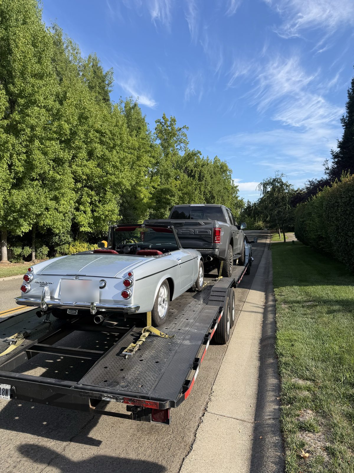 Classic convertible on the open trailer behind the truck